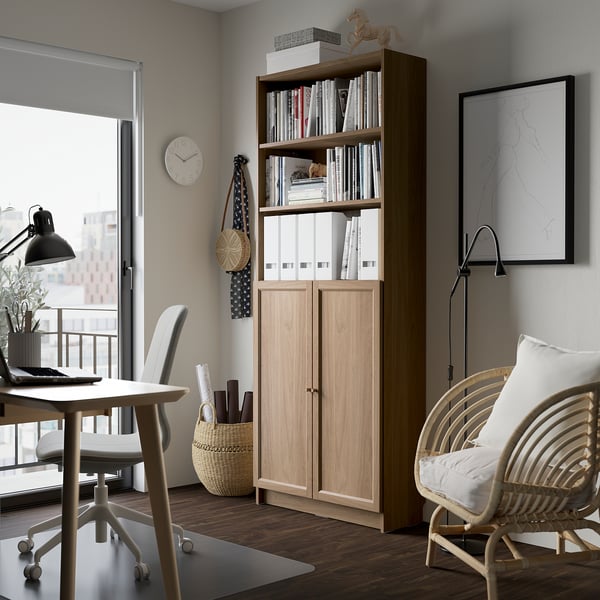 BILLY boekenkast in licht hout naast bureau, stoel, bij balkon. Boeken & decor, past in moderne minimalistische kamer.
