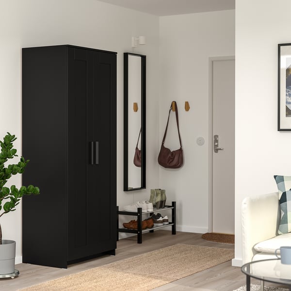Minimalistische entree met hoge BRIMNES kledingkast, spiegel, beige vloerkleed en witte stoel.
