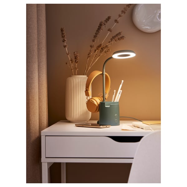 Modern bureau met groene BRUNBÅGE lamp, witte vaas, droogbloemen, koptelefoon, pennen en notitieboekjes.