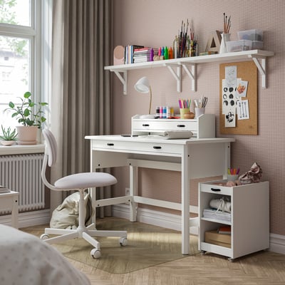 Wit bureau in de kamer met stoel, planken en raam. Middelgroot formaat met lade en bovenblad, ideaal voor studeren of hobby's.
