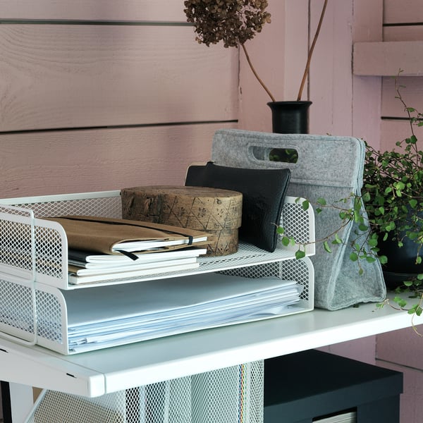 Wit metalen mesh document organizers op een plank, met papieren en boeken, met grijze vilten dozen en een plant.