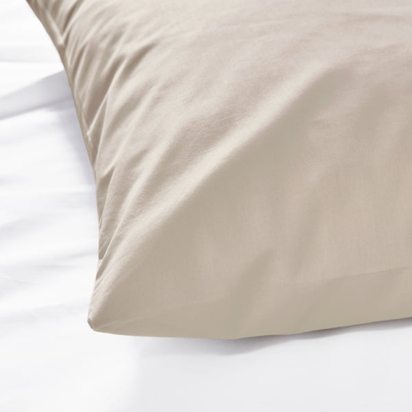 Gladde, beige kussensloop op een bed, met een zachte, hoogwaardige katoenen textuur.