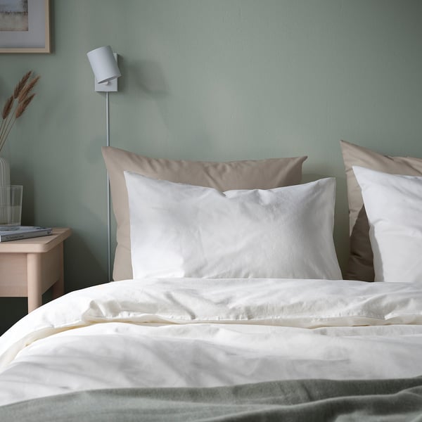 DVALA witte kussenslopen & beddengoed op matras, wandlampje, klein nachtkastje met glas, decor. Zacht, natuurlijk katoen.