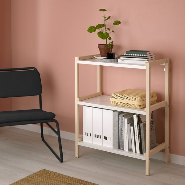 Kleine, beige EKENABBEN plank houdt boeken & decor naast zwarte stoel.
