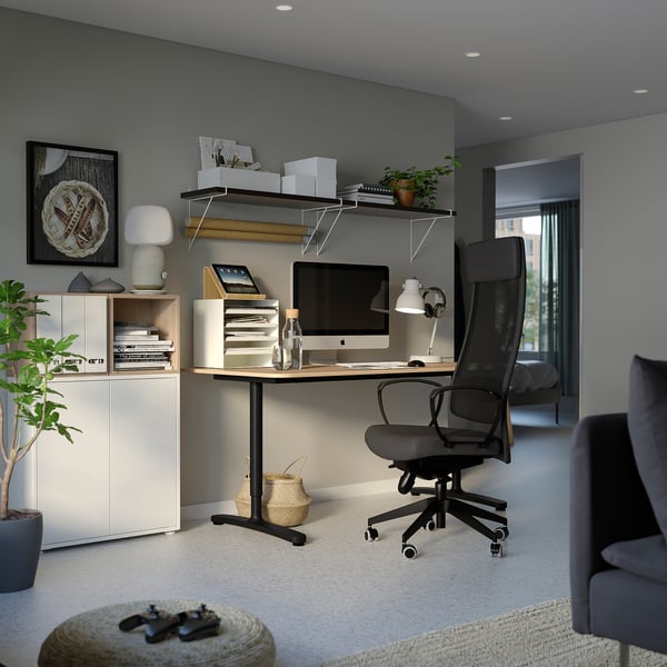 Modern kantoor aan huis, een EKET witte opbergunit, houten bureau, zwarte bureaustoel en diverse decoratieve artikelen.
