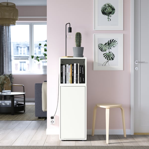 Witte EKET kast, zwarte lamp, plant, roze muur prints, kruk, woonkamer.