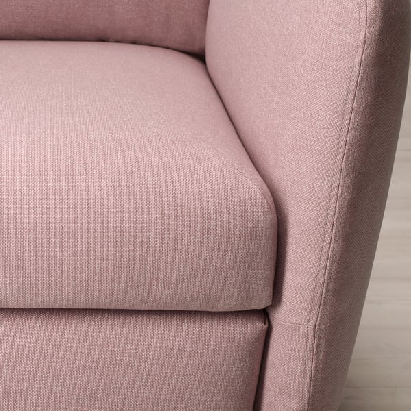 Close-up van een zachte, roze stoffen stoel met afgeronde armleuningen en gedempte zitting, met de nadruk op comfort en kwaliteit.