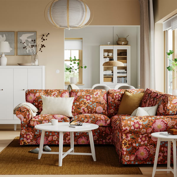 EKTORP hoekbank in de woonkamer met bloemenprint en witte decoratie.