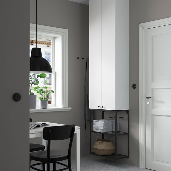 Witte UNIT-hoge kast, open zwarte plank, klein bureau en stoel, hanglamp, plant.