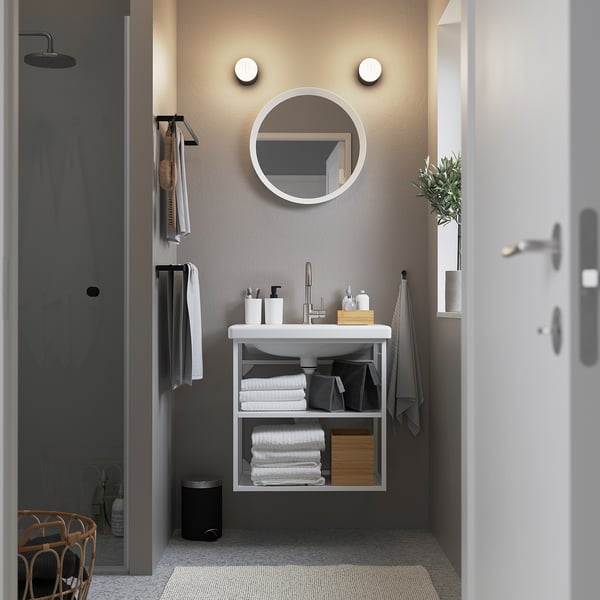 Moderne badkamer: aan de muur gemonteerde witte wastafel met ronde spiegel, minimalistische stijl.