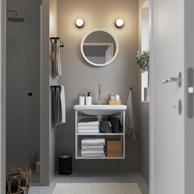 Moderne badkamer: aan de muur gemonteerde witte wastafel met ronde spiegel, minimalistische stijl.