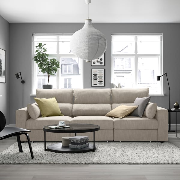 Een moderne woonkamer met een ESKILSTUNA-bank, salontafel, vloerkleed, hanglamp en ramen.