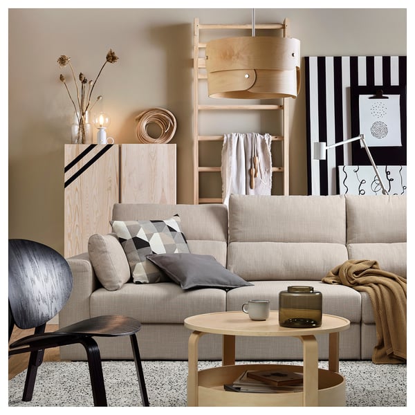 Moderne woonkamer met beige ESKILSTUNA-bank, houten salontafel, grijze fauteuil en natuurlijke inrichting.