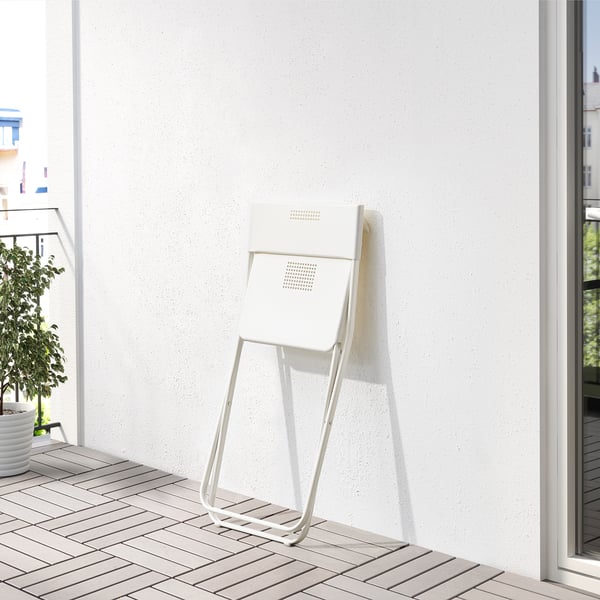 Opvouwbare witte stoel op betegeld balkon, perfect voor kleine ruimtes.