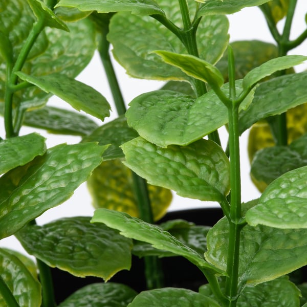 Close-up van levendige, realistische groene bladeren van een kunstmatige plant in pot.