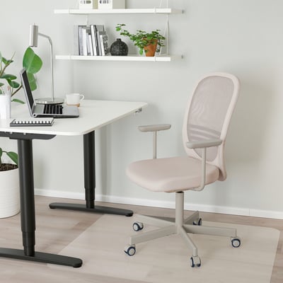 Witte IKEA FLINTAN bureaustoel met mesh rugleuning, naast bureau met laptop, compact en ergonomisch voor lange werkuren.