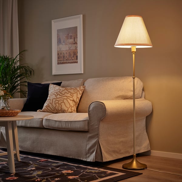 Moderne woonkamer met FLYGHÖJD lamp, beige bank, plant en kunst aan de muur.