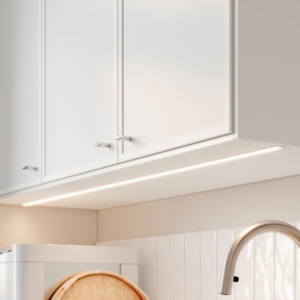 Witte keukenkast met geïntegreerde LED-lichtstrip onder de plank, met een modern minimalistisch ontwerp.