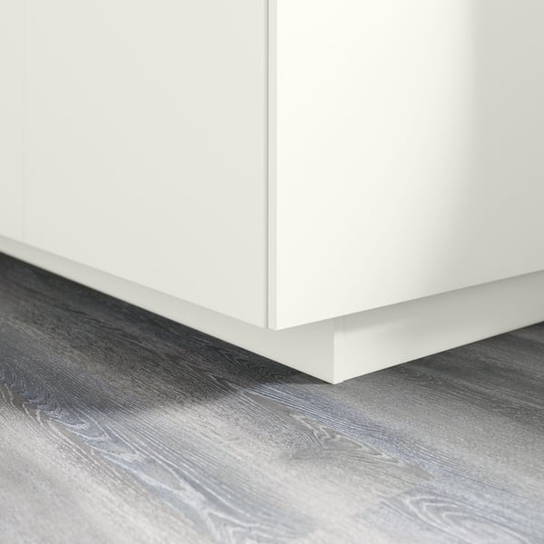 Witte keukenkastsokkel op grijze houten vloer. Dekt de opening tussen vloer- en onderkasten. Onderdeel van de FÖRBÄTTRA-serie.