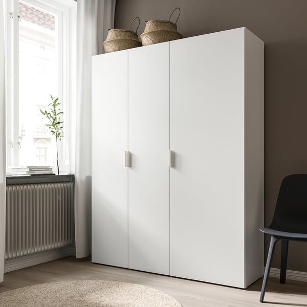 Een hoge, strakke witte FONNES kast met twee deuren staat tegen een muur. Het heeft gevlochten manden aan de bovenkant en een moderne esthetiek.