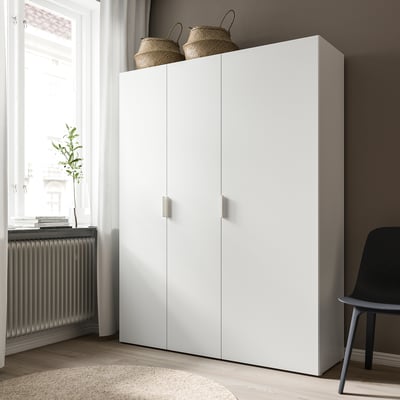 Een hoge, strakke witte FONNES kast met twee deuren staat tegen een muur. Het heeft gevlochten manden aan de bovenkant en een moderne esthetiek.