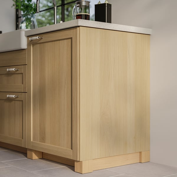 Een moderne keuken met lichte houten kasten, met lichtgekleurde werkbladen en strakke lijnen.