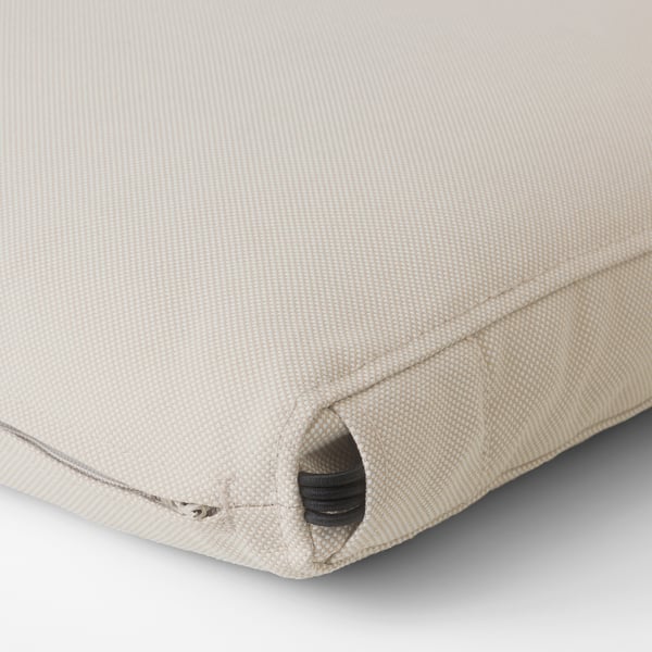Close-up van een goed gemaakt, beige buitenkussen, met een stevige ritssluiting en fijne stiksels, die de kwaliteit en duurzaamheid benadrukken.