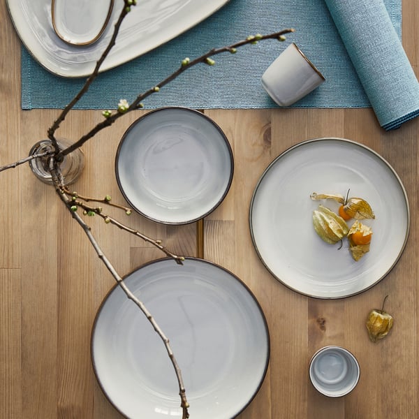 GLADELIG schaal: zandgeglazuurd, steengoed, ronde, handgemaakte look. Kleiner dan omringende platen, in het midden geplaatst.