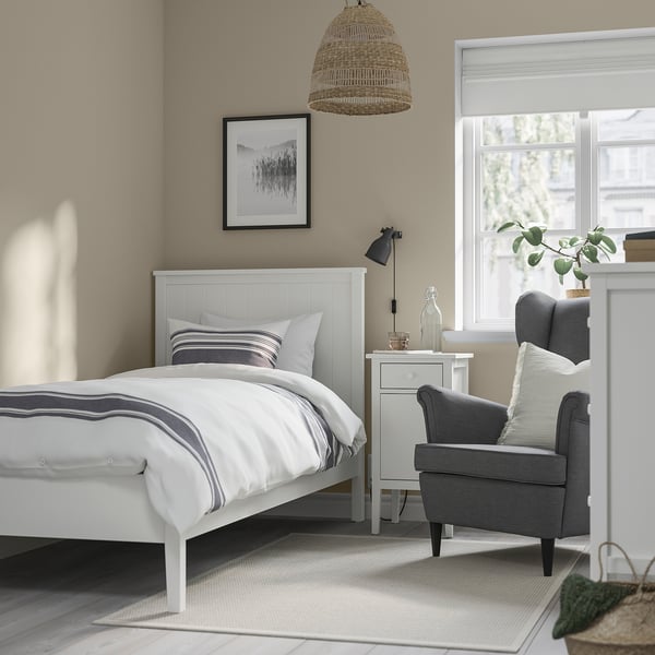 GULLABERG-bed in een gezellige slaapkamer met grijze stoel, moderne inrichting, houten hoofdeinde en tapijt.