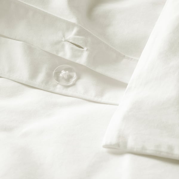 Close-up van fris wit beddengoed met een prominente enkele witte knoop. De stof heeft fijne stiksels en een luxueuze, gladde textuur.