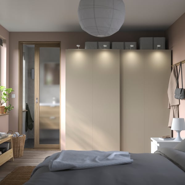 Moderne slaapkamer met schuifdeuren, grijs beddengoed en hangende jassen. Zachte verlichting en een minimalistische inrichting.