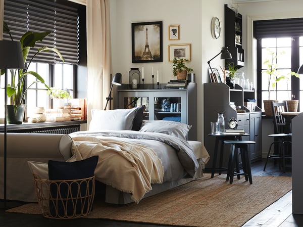Moderne slaapkamer met wit bed, houten vloer en zwarte HAUGA kast; Neutrale tinten, natuurlijk licht.