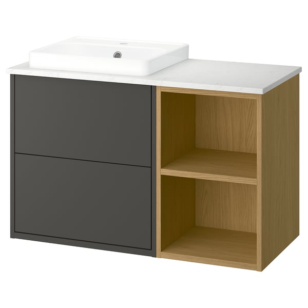 Een moderne badkamermeubel genaamd HAVBÄCK in donkergrijs en licht eikenhout, met een marmeren aanrechtblad, een witte keramische wastafel, twee lades en open planken.
