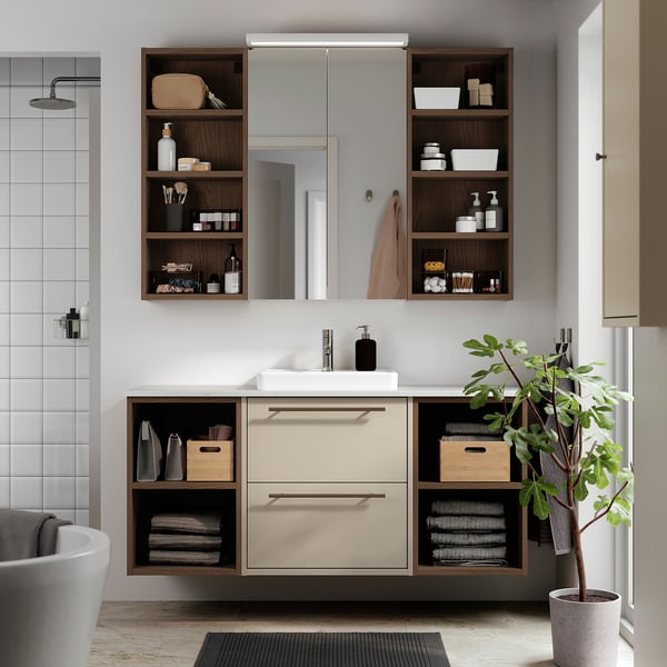 Moderne badkamer met beige HAVBÄCK kaptafel. Lades, planken en een witte wastafel. Versierd met handdoeken en planten.