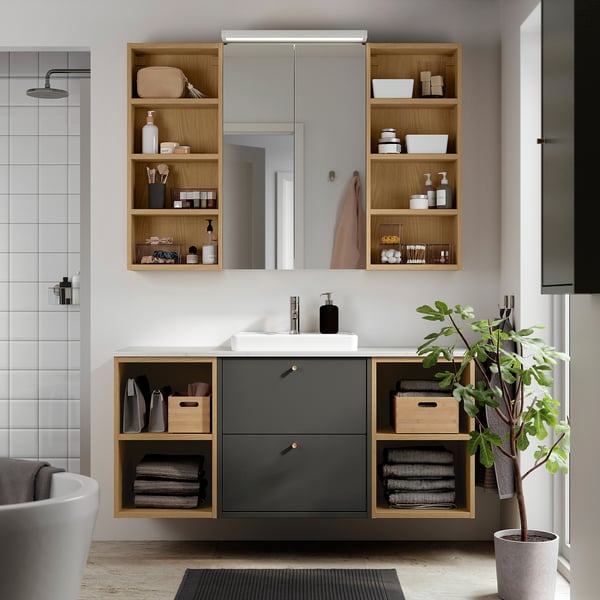 Moderne badkamer met een HAVBÄCK donkergrijze wastafel, open houten planken en een witte wastafel; minimalistisch ontwerp met ruime aanrechtruimte.