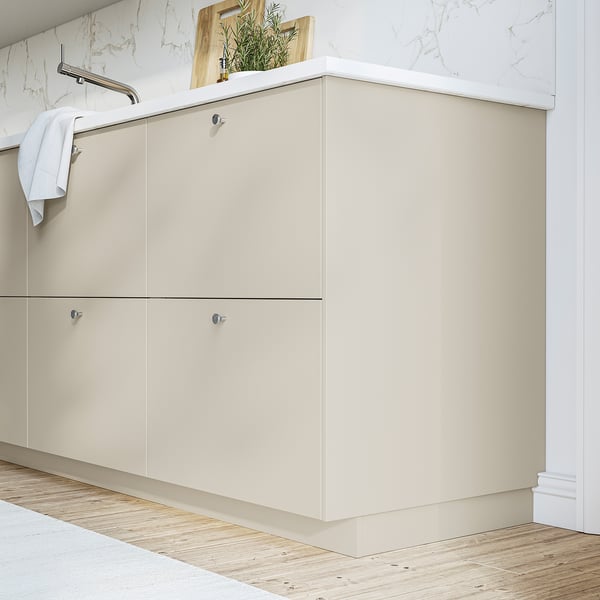 Beige HAVSTORP kast met gladde oppervlakken vormt een aanvulling op marmeren muren en houten vloeren en biedt voldoende opbergruimte voor een moderne badkamer.
