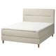 Modern beige bed met zacht hoofdeinde, houten poten en witte matras.