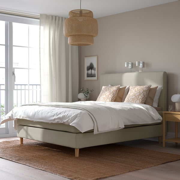 Moderne neutrale slaapkamer met HEMFJÄLLET bed, wit beddengoed, houten nachtkastje, raam met gordijnen.
