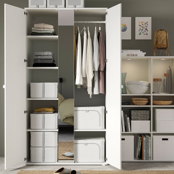 Georganiseerde kast met HEMMAFIXARE opbergdozen, opgevouwen kleding, hangende kledingstukken en boekenplanken.