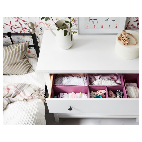 Slaapkamer met witte HEMNES kist, gladde lades en kunst aan de muur. Planten in de vaas voegen decor toe.