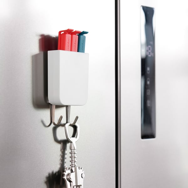 Witte magnetische organizer op een metalen oppervlak bevat gekleurde markeringen en sleutels.