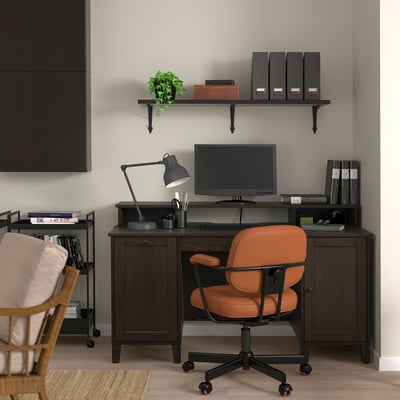 Moderne thuiskantooropstelling: donker houten bureau, oranje stoel, computer, planken met boeken & plant.