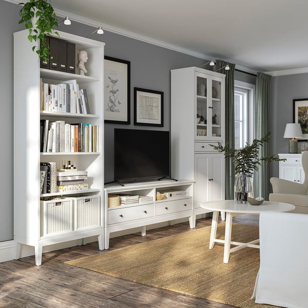 Witte IDANÄS woonkamerindeling: modern, houten, boekenplanken, tv-meubel, soft-close lades, lichtgrijze wanden, vloerkleed, stoelen met kussens, glazen kast.