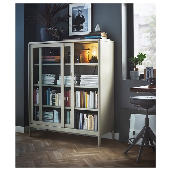 Modern kantoor met IDÅSEN boekenkast, glazen deuren, boeken. Bureau, stoel, donkerblauwe muren, grote ramen.