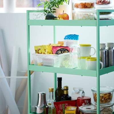-tier IKEA rek met planten, producten, snacks, & flessen.