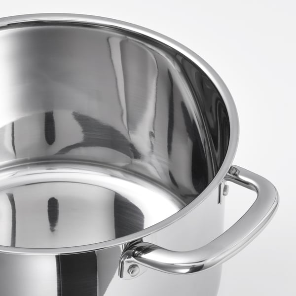 Gepolijste roestvrijstalen steelpan met groot handvat en gebogen binnenkant, die licht weerkaatst.