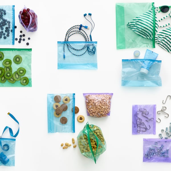 Diverse herbruikbare zipbags met diverse inhoud zoals fruit, snacks, technologische accessoires en hardware, wat organisatie en veelzijdigheid illustreert.