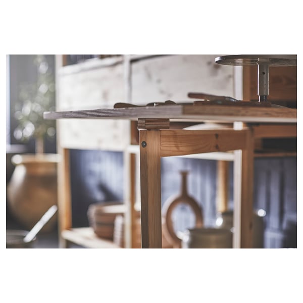 Een houten IVAR-tafel in een kamer, natuurlijke afwerking, met metalen beslagen.