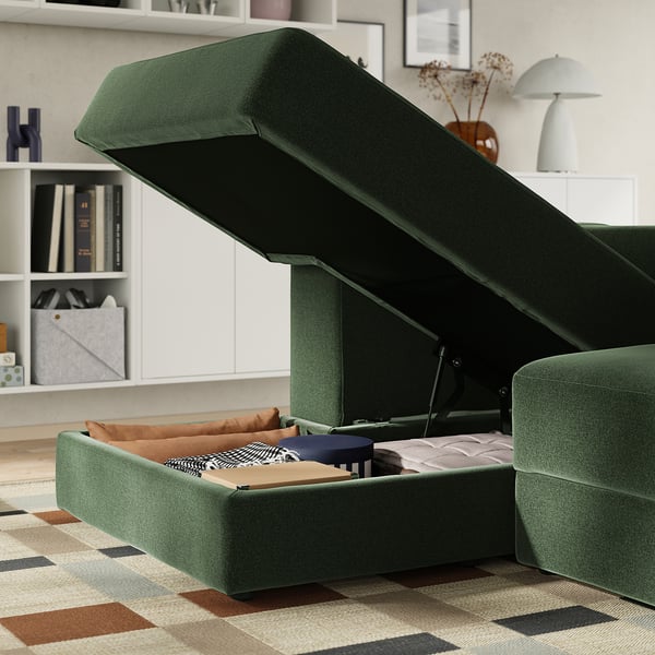Groene bank met chaise longue, open opbergruimte voor dekens, zachte kussens.