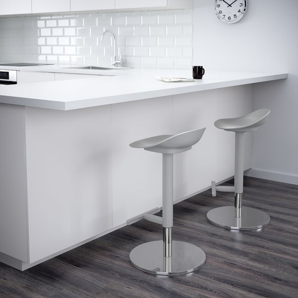 Moderne keuken met witte werkbladen en twee verstelbare barkrukken met ronde onderstellen.